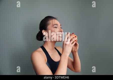 Femme souriante mangeant un hamburger et profitant d'un moment de restauration rapide Banque D'Images
