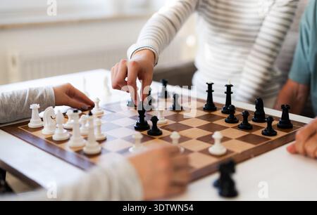 Famille jouant aux échecs à la maison, figures en mouvement sur le plateau Banque D'Images