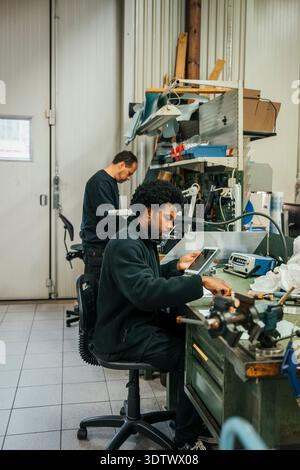 Fabricant masculin travaillant tout en étant assis à la table dans l'usine Banque D'Images