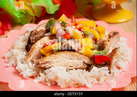Poulet grillé savoureux servi sur du riz cuit à la vapeur, garni d'une garniture tropicale vibrante de mangue, de poivrons, d'oignons et de jalapenos, avec un soupçon de Banque D'Images