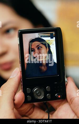 Gros plan d'une personne photographiant une femme à travers un vieil appareil photo numérique Banque D'Images