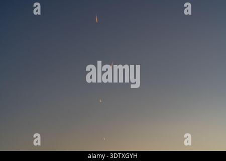 Plusieurs traînées de vapeur orange incandescente se répandant dans un ciel sombre au coucher du soleil Banque D'Images