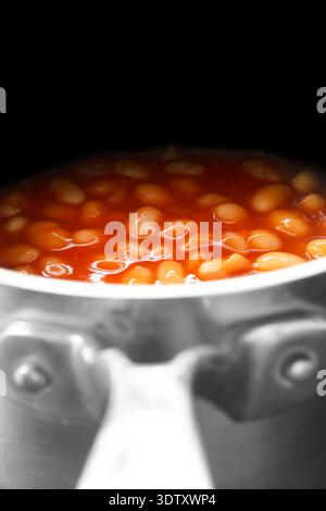 Haricots cuits en conserve, dans une sauce tomate, cuits dans une casserole en acier inoxydable fond Banque D'Images