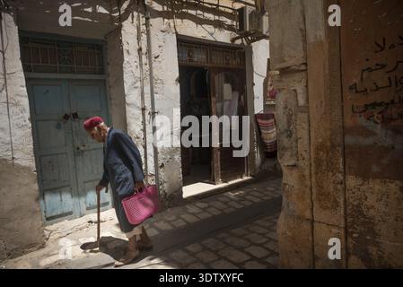 Un vieil homme tunisien portant une Chéchie rouge traditionnelle marche dans les ruelles étroites de la Médine de Sfax, Tunisie, Afrique du Nord Banque D'Images