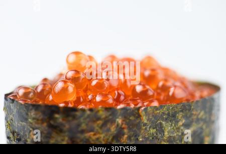 Gros plan de sushi ikura gunkan mettant l'accent sur la texture scintillante des œufs de saumon. Les œufs de poisson orange éclatants se distinguent magnifiquement sur le dos mou Banque D'Images