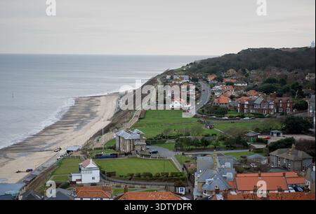 Une vue aérienne de la ville côtière de Cromer, Norfolk, située sur la côte de la mer du Nord. La perspective met en évidence l'architecture victorienne, l'église Saint-Pierre et Saint-Paul du XIVe siècle avec sa tour de 160 pieds, et la jetée classée Grade II, qui a ouvert ses portes en 1901. Historiquement un petit village de pêcheurs connu pour son 'crabe Cromer', la ville s'est développée en une station balnéaire populaire à la fin du XIXe siècle après l'arrivée du Great Eastern Railway. La vue englobe le paysage de falaise, les plages de sable et la disposition dense du centre-ville historique. Banque D'Images
