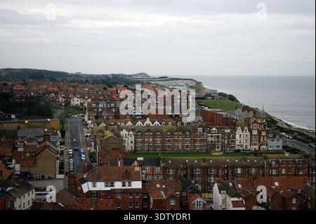 Une vue aérienne de la ville côtière de Cromer, Norfolk, située sur la côte de la mer du Nord. La perspective met en évidence l'architecture victorienne, l'église Saint-Pierre et Saint-Paul du XIVe siècle avec sa tour de 160 pieds, et la jetée classée Grade II, qui a ouvert ses portes en 1901. Historiquement un petit village de pêcheurs connu pour son 'crabe Cromer', la ville s'est développée en une station balnéaire populaire à la fin du XIXe siècle après l'arrivée du Great Eastern Railway. La vue englobe le paysage de falaise, les plages de sable et la disposition dense du centre-ville historique. Banque D'Images