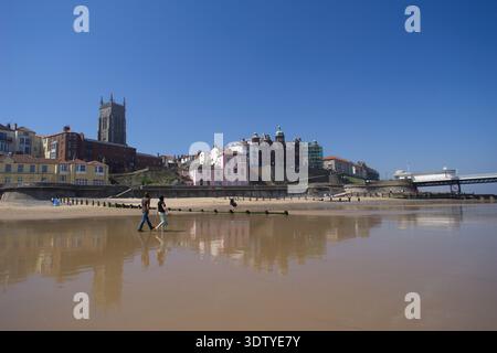 Une vue aérienne de la ville côtière de Cromer, Norfolk, située sur la côte de la mer du Nord. La perspective met en évidence l'architecture victorienne, l'église Saint-Pierre et Saint-Paul du XIVe siècle avec sa tour de 160 pieds, et la jetée classée Grade II, qui a ouvert ses portes en 1901. Historiquement un petit village de pêcheurs connu pour son 'crabe Cromer', la ville s'est développée en une station balnéaire populaire à la fin du XIXe siècle après l'arrivée du Great Eastern Railway. La vue englobe le paysage de falaise, les plages de sable et la disposition dense du centre-ville historique. Banque D'Images