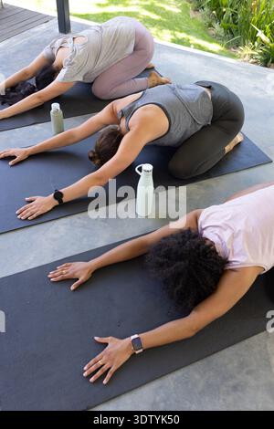Trois tapis de yoga noirs sont couchés sur un patio en béton couvert avec deux bouteilles légères à proximité Banque D'Images
