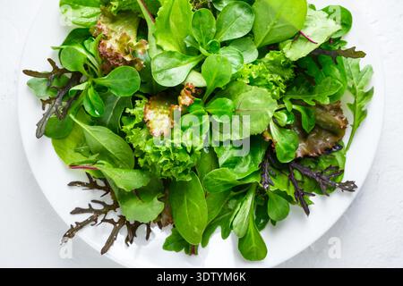 Salades vertes mélangées disposées lâchement avec une variété feuillue. Les légumes frais créent un fond alimentaire sain Banque D'Images