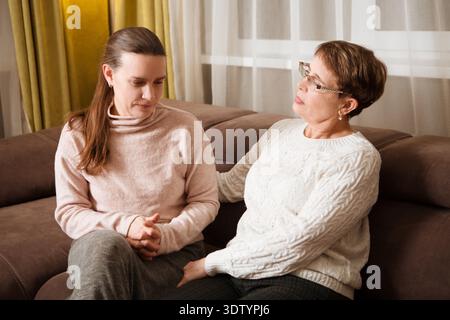 consoles de mère senior, réconfortant la fille adulte adulte triste assise au canapé à la maison. Assistance dans deux générations || autorisation du modèle Banque D'Images