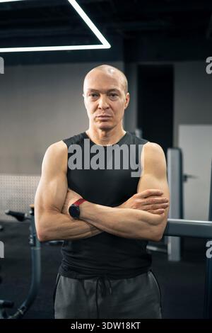 Homme posant avec les bras croisés dans le portrait de gymnastique Banque D'Images