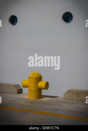 La borne d'amarrage jaune audacieuse contraste minimaliste avec la coque blanche lisse d'un navire amarré à Nassau, aux Bahamas, créant un geomet propre Banque D'Images