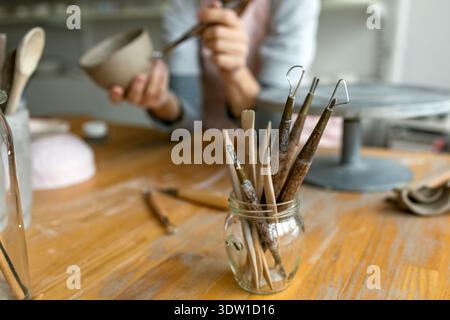 Gros plan des mains d'un potier travaillant avec un objet en argile dans son atelier Banque D'Images