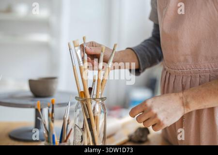 Gros plan d'un artiste travaillant avec de la peinture dans un atelier de poterie Banque D'Images
