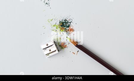 Crayon de couleur et taille-crayon en métal sur fond blanc. Copeaux de bois et pigment coloré sur une table blanche. Art, créativité, passe-temps et éducation co Banque D'Images