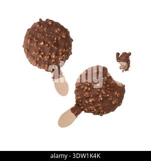 Chocolat au lait et noix d'amande écrasées recouvertes de crème glacée ronde sur bâton en bois, entière et mordue volant sur fond blanc. Noix de chocolat sucré POPS Banque D'Images