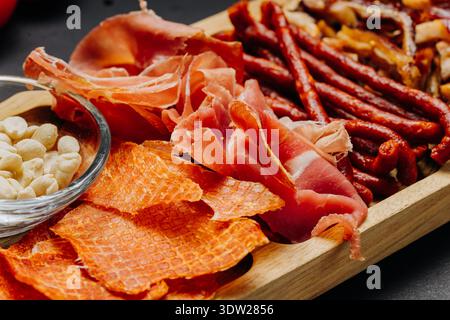 Assortiment de charcuteries et d'en-cas servis sur un plateau de hors-d'œuvre gastronomique en bois Banque D'Images