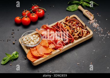 Assortiment de charcuteries et d'en-cas servis sur un plateau de hors-d'œuvre gastronomique en bois Banque D'Images