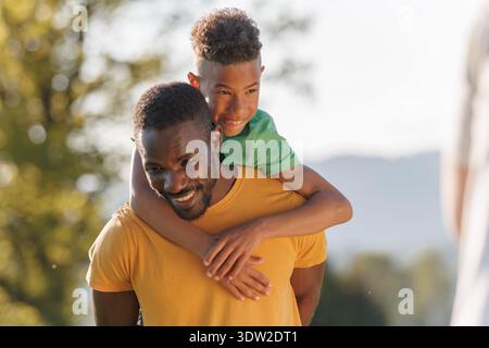 Un père célibataire et son fils partagent des moments amusants en plein air alors qu'ils s'engagent dans des activités ludiques pendant un coucher de soleil chaud. Banque D'Images