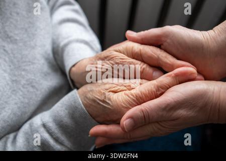 Mains douces d'un soignant tenant la main d'une personne âgée montrant confort et compassion Banque D'Images