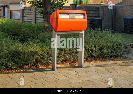 une boîte aux lettres publique orange dans les rues d'un village des pays-bas pour jeter vos lettres dedans Banque D'Images