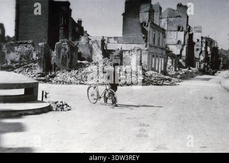 Civils dans la ville dévastée de Lisieux après le raid aérien allié du 6 juin 1944. Le 6 juin 1944, une énorme force d'invasion Alllied impliquant 7000 navires et 140 000 hommes débarque avec succès sur les côtes françaises et établit cinq têtes de plage. Une campagne de tromperie réussie signifiait qu'une grande partie de la résistance allemande était à Calais et que les pertes étaient relativement peu nombreuses compte tenu de l'ampleur et des dangers de l'opération. De nombreuses villes françaises historiques ont été détruites avant et pendant les débarquements. Banque D'Images