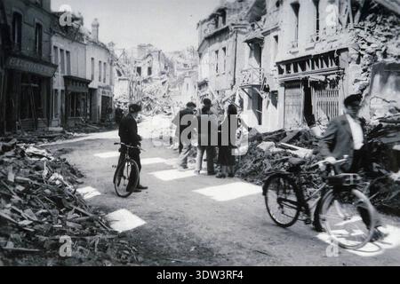 Civils dans la ville dévastée de Lisieux après le raid aérien allié du 6 juin 1944. n le 6 juin 1944, une énorme force d'invasion Alllied impliquant 7000 navires et 140 000 hommes débarque avec succès sur les côtes françaises et établit cinq têtes de plage. Une campagne de tromperie réussie signifiait qu'une grande partie de la résistance allemande était à Calais et que les pertes étaient relativement peu nombreuses compte tenu de l'ampleur et des dangers de l'opération. De nombreuses villes françaises historiques ont été détruites avant et pendant les débarquements. Banque D'Images