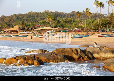 Une scène de plage tranquille avec des bateaux de pêche et des palmiers sous un ciel ensoleillé à Goa, en Inde. Banque D'Images