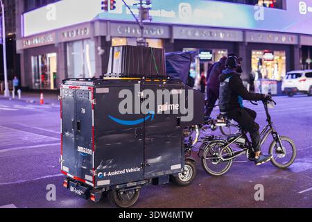 New-York, États-Unis, 1er novembre 2025 : livreur Amazon Prime chevauchant un vélo de fret électrique dans la rue de la ville la nuit avec des lumières urbaines Banque D'Images