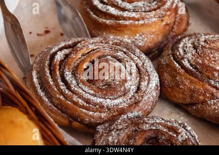 Gros plan d'un rouleau de cannelle fraîchement cuit avec des couches tourbillonnantes de pâte et de fourrage à la cannelle, mettant en valeur sa texture douce et sa croûte dorée Banque D'Images