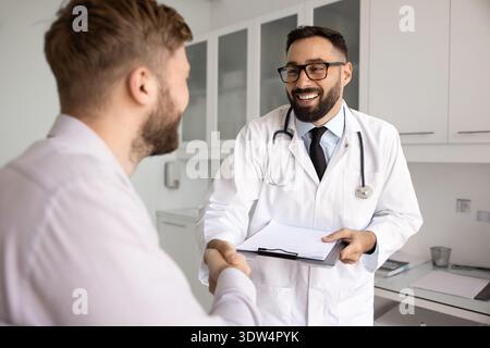 Heureux sourire jeune médecin masculin serrant la main avec un patient reconnaissant Banque D'Images