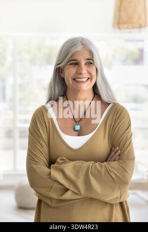 Femme pensive d'âge moyen posant seule dans le salon Banque D'Images