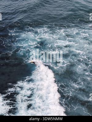 Vue aérienne de la mer turbulente envoûtante avec sa mousse blanche contrastant magnifiquement avec les eaux bleues profondes, Siargao, Caraga, Philippines. Banque D'Images