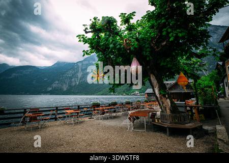 Café en plein air assis au bord d'un lac avec des montagnes et un ciel orageux en arrière-plan Banque D'Images