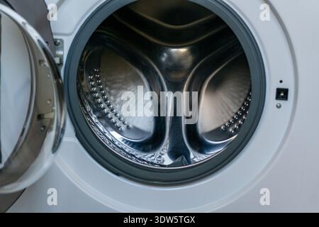 Vue rapprochée d'un lave-linge ouvert à chargement frontal avec tambour vide en acier inoxydable. Banque D'Images