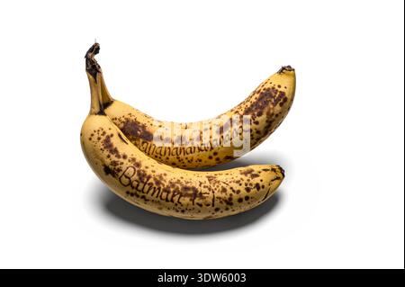 Deux bananes mûres avec des taches brunes reposent sur un fond blanc, chacune présentant un message manuscrit. On lit 'Banananananananana', tandis que l'autre sa Banque D'Images