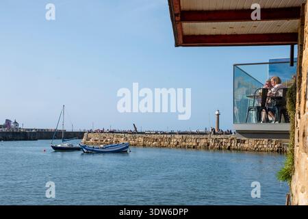 Yorkshire, Royaume-Uni – 24 juillet 2025 : les touristes apprécient la vue depuis un balcon surplombant le port de Whitby Banque D'Images