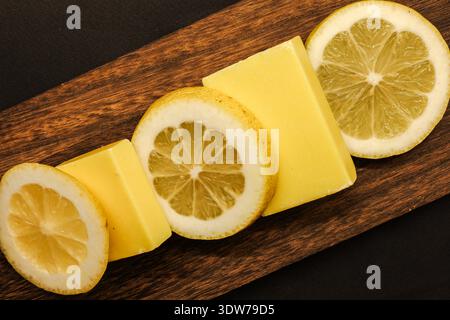 Composition minimale à plat avec savon au citron fait à la main et agrumes frais sur une planche de bois. Parfait pour la beauté propre, thèmes spa Banque D'Images
