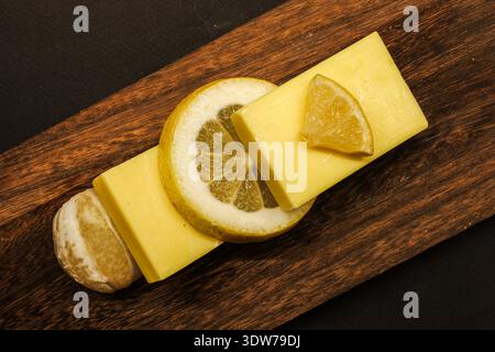 Composition minimale à plat avec savon au citron fait à la main et agrumes frais sur une planche de bois. Parfait pour la beauté propre, thèmes spa Banque D'Images