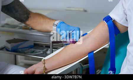 Un travailleur de la santé effectue un prélèvement sanguin sur le bras d'un patient dans un environnement clinique. Banque D'Images