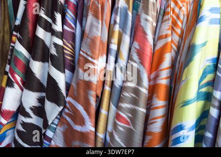 Tissus et textiles Ikat colorés et à motifs exposés suspendus sur un marché, présentant des imprimés de style ikat, des motifs de coup de pinceau audacieux et une variété de colo Banque D'Images