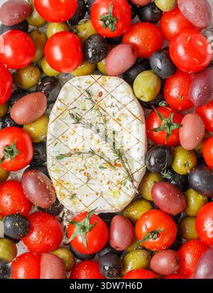 Fromage avec moisissure blanche (camembert, brie) pour la cuisson avec tomates cerises, olives noires et vertes, kalamata, thym et huile d'olive gros plan. Sélectif fo Banque D'Images