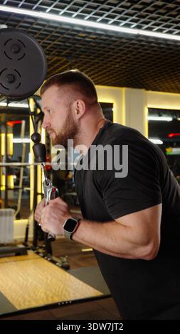 Homme fort debout et posant dans l'intérieur moderne de la salle de gym Banque D'Images