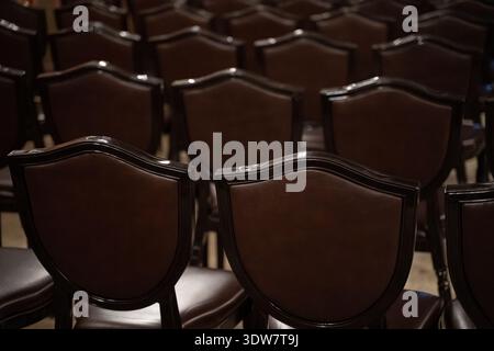 Gros plan de chaises en bois vides disposées en rangées. Banque D'Images