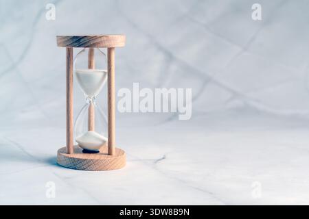 Sablier en bois classique avec du sable blanc coulant, symbolisant la gestion du temps et les délais Banque D'Images