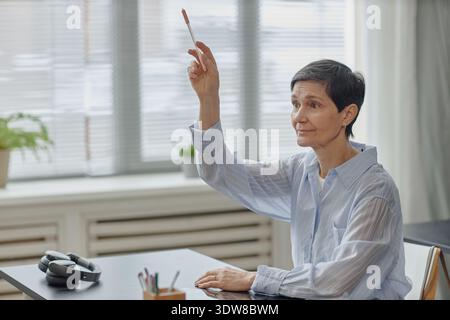 Femme caucasienne senior levant la main tout en participant à la discussion en classe Banque D'Images