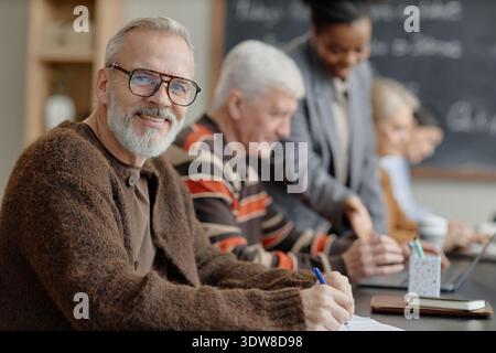 Portrait d'un homme caucasien senior souriant tout en assistant à la classe d'éducation des adultes Banque D'Images