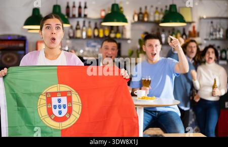 Les fans du drapeau du Portugal célèbrent la victoire de leur équipe préférée au bar à bière Banque D'Images