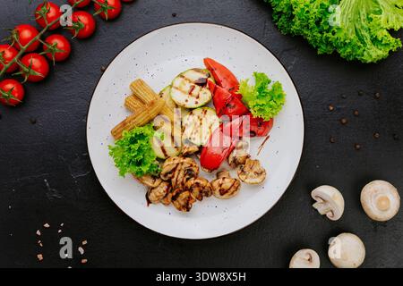 Légumes grillés avec champignons courgettes et poivre servis sur assiette sur fond foncé Banque D'Images